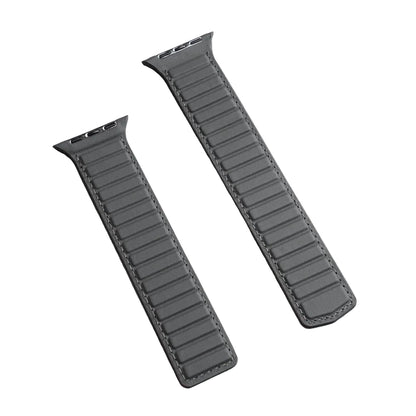 Two dark gray leather watch straps with stitched edges, laid diagonally on a textured light gray surface.